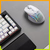 Glorious Model I 2 Wireless Gaming Mouse Dual Mode 2.4Ghz & Bluetooth 75g Superlight with 9 Buttons 2 Swappable and Side Thumb Rest 49 Model I 2 Wireless in White in a black and white desk setup