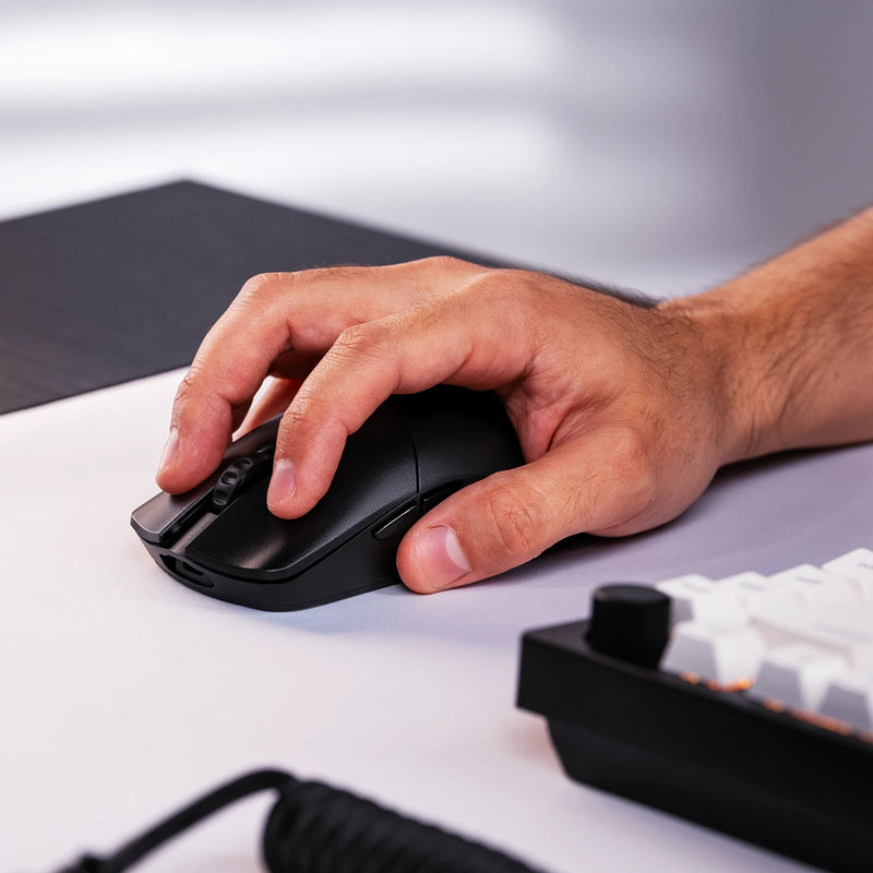 A close-up of a hand using a Model O 2 PRO Series Wireless Mouse 4K/8KHz Edition on a white mousepad, with a GMMK PRO 75% partially visible in the background.