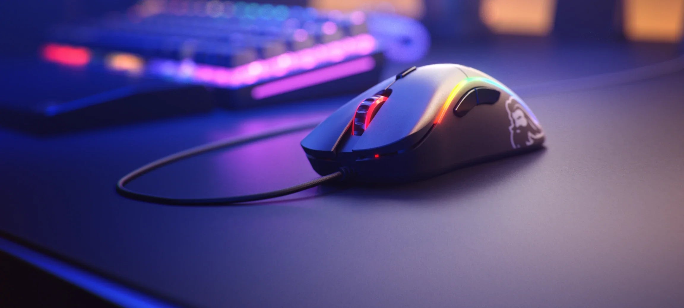 Model D Wired mouse in Matte Black shown in a desktop setup with purple lighting