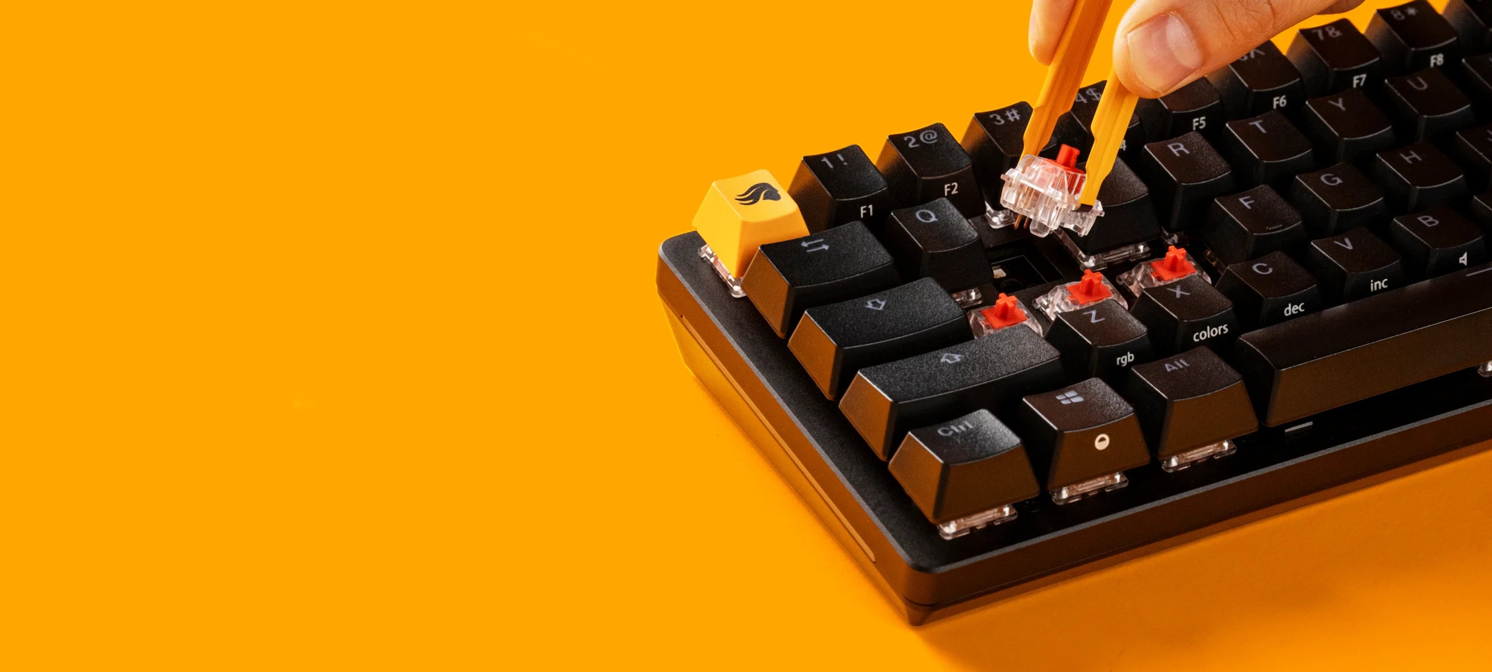 GMMK 2 Black Keyboard having switch removed with a switch puller on an orange background