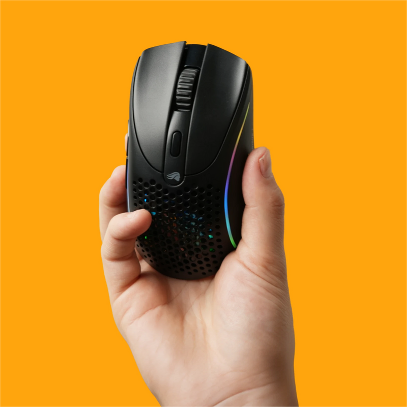 Hand holding up the Model D 2 Wireless in Black on an orange background