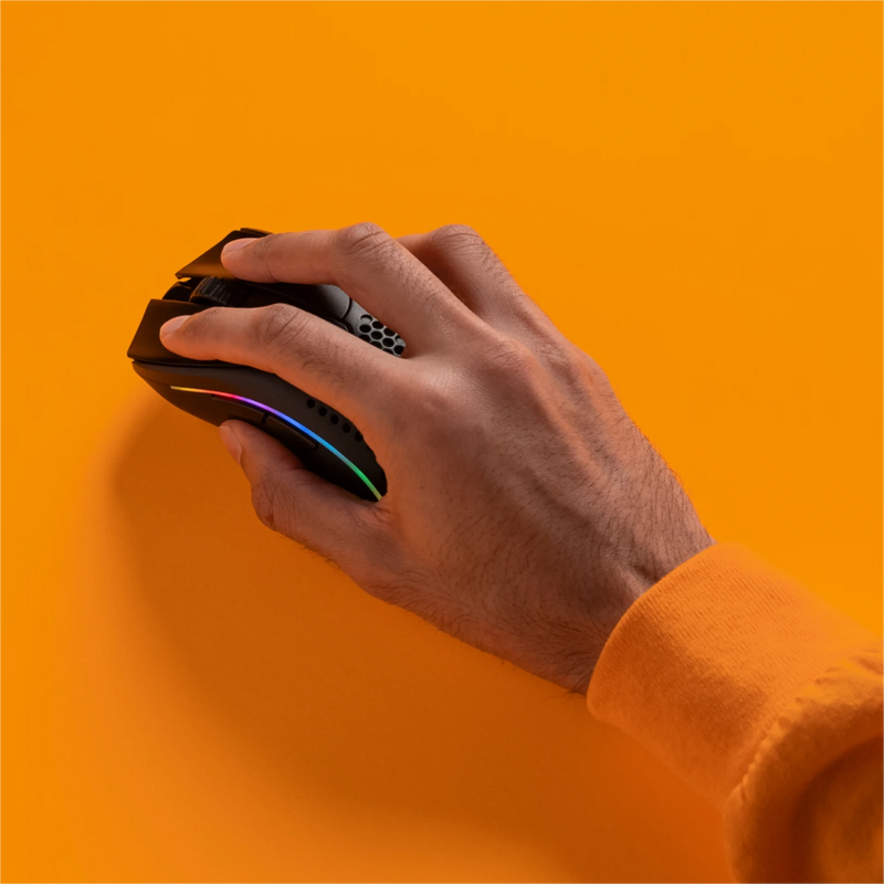 Top view of a hand holding a Model D 2 Wireless in Black with a standard grip on an orange background