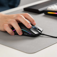Right side view of a hand using a Model O 2 Wired in Black on top of a grey mousepad next to a GMMK PRO and wooden wrist rest